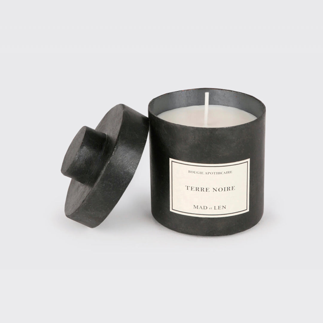 Bougie Parfumée Terre Noire de MAD et LEN est composé de terre primal, humus, écorce, bois pétrifié, cèdre, champignon et sous bois. Conçu pour 65h de combustion à base de cire blanche 100% végétale